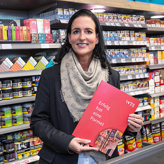 Frau mit Prospekt vor Supermarktregal